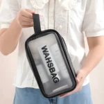 Cosmetiquera transparente negra modelo Washbag, sosteniendo varios productos.
