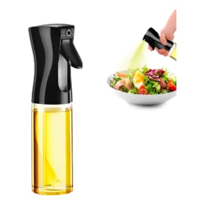 Dispensador de aceite en aerosol de vidrio y tapa negra, rociando un chorro fino sobre una ensalada fresca con huevo y tomate.