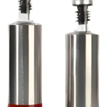 Dos dispensadores de aceite tipo vertedor, cuerpo metálico plateado, base inferior transparente con líquido rojizo oscuro.