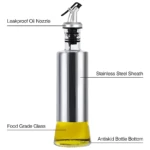 Dispensador de aceite con cuerpo de vidrio y revestimiento de acero inoxidable, boquilla antiderrames y base antideslizante.