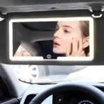 Espejo de visera con luz LED para coche. Una mujer aplica base de maquillaje en su rostro con la ayuda de la iluminación.