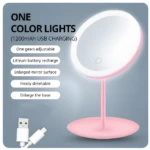 Espejo de maquillaje rosa con luz LED circular, base ancha y USB recargable.