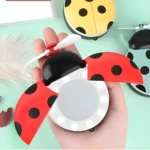 Espejo LED abanico ladybug rojo con alas abiertas, portátil y recargable USB para maquillaje.