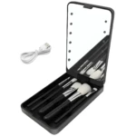 Estuche negro con espejo LED y set de brochas de maquillaje, incluye cable USB blanco.