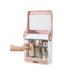 Espejo organizador de maquillaje rosa y blanco con compartimentos y frascos de cosméticos, mano colocando producto.