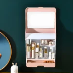Organizador de maquillaje rosa con espejo, tapa protectora y compartimentos para cosméticos.