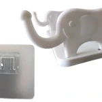 Gancho pared adhesivo blanco plástico forma elefante sonriente, incluye base pegante cuadrada transparente.
