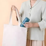 Mujer coloca estuche azul para cepillo dental en bolsa blanca.