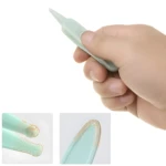 Mano sosteniendo extractor nasal plástico color menta punta fina; detalles muestran puntas redondeadas con malla de textura y borde dorado.