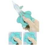Extractor nasal manual celeste con forma de oso. Dedo presionando botón, flechas muestran succión de moco a través de la boquilla de silicona.