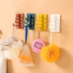 Ganchos adhesivos giratorios de 5 brazos en colores rosa, azul, amarillo y blanco para organizar accesorios de baño y llaves.