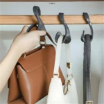 Set de 5 ganchos organizadores grises colgando 3 bolsos (2 de cuero, 1 blanco) y un cinturón negro en un armario.