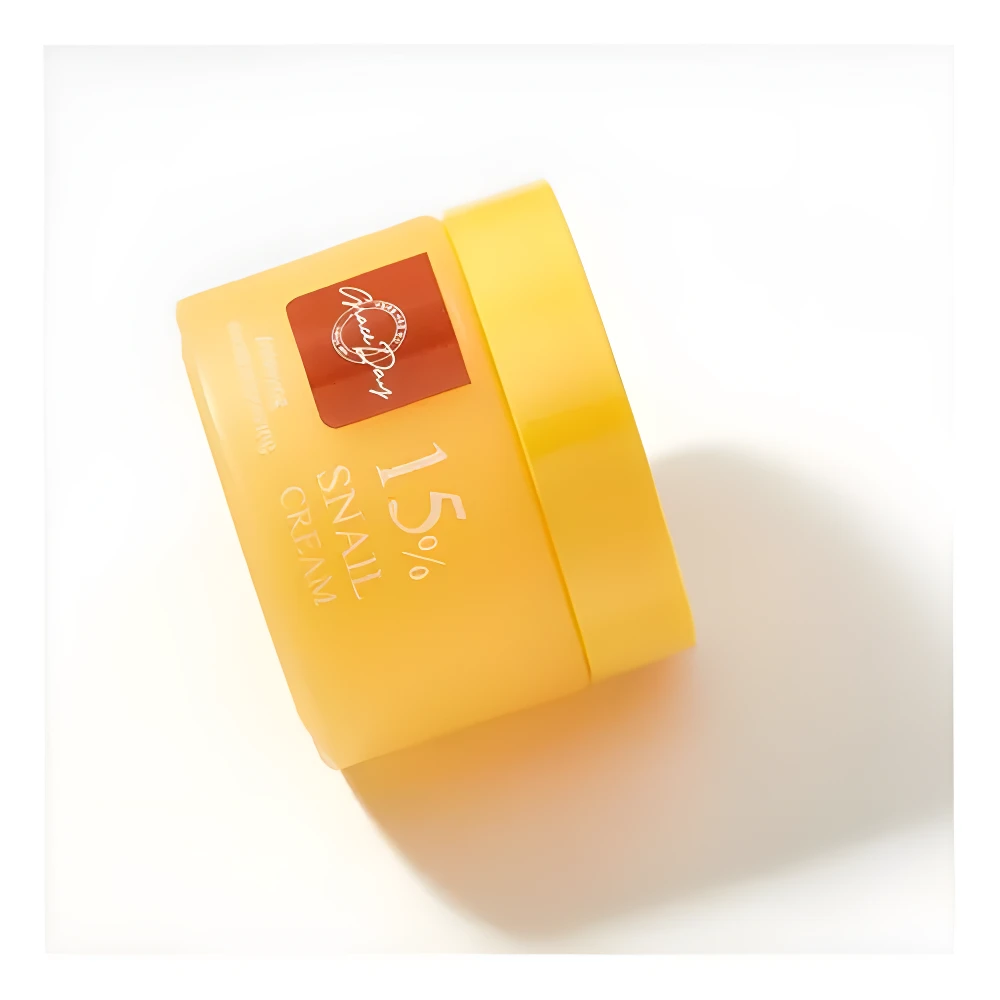 Tarro inclinado amarillo de crema facial Grace Day 15% Snail Cream sobre fondo blanco.