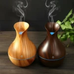 Humidificadores difusores USB diseño jarra, uno en madera clara, otro en madera oscura, liberando vapor en ambiente.