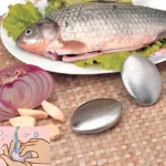 Set de jabones metálicos para manos junto a pescado, cebolla y ajo, mostrando uso con agua para quitar olores.