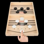 Juego de mesa Foosball de madera con discos blancos y negros. Un dedo interactúa con un disco.