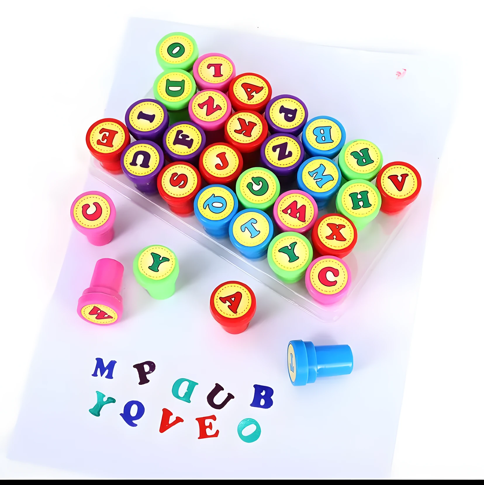 Sellos de abecedario de colores vibrantes, letras en goma y cuerpos plásticos, sobre papel blanco con algunas letras estampadas.