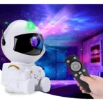Proyector luz nocturna astronauta blanco proyectando nebulosa azul y rosa con estrellas, control remoto en mano.
