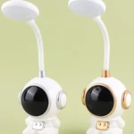 Dos lámparas de escritorio LED flexibles con base en forma de astronauta blanco, una con detalles plateados y otra con detalles dorados.