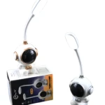 Lámpara LED de escritorio recargable forma astronauta blanco con detalles dorados, flexible, junto a su caja.