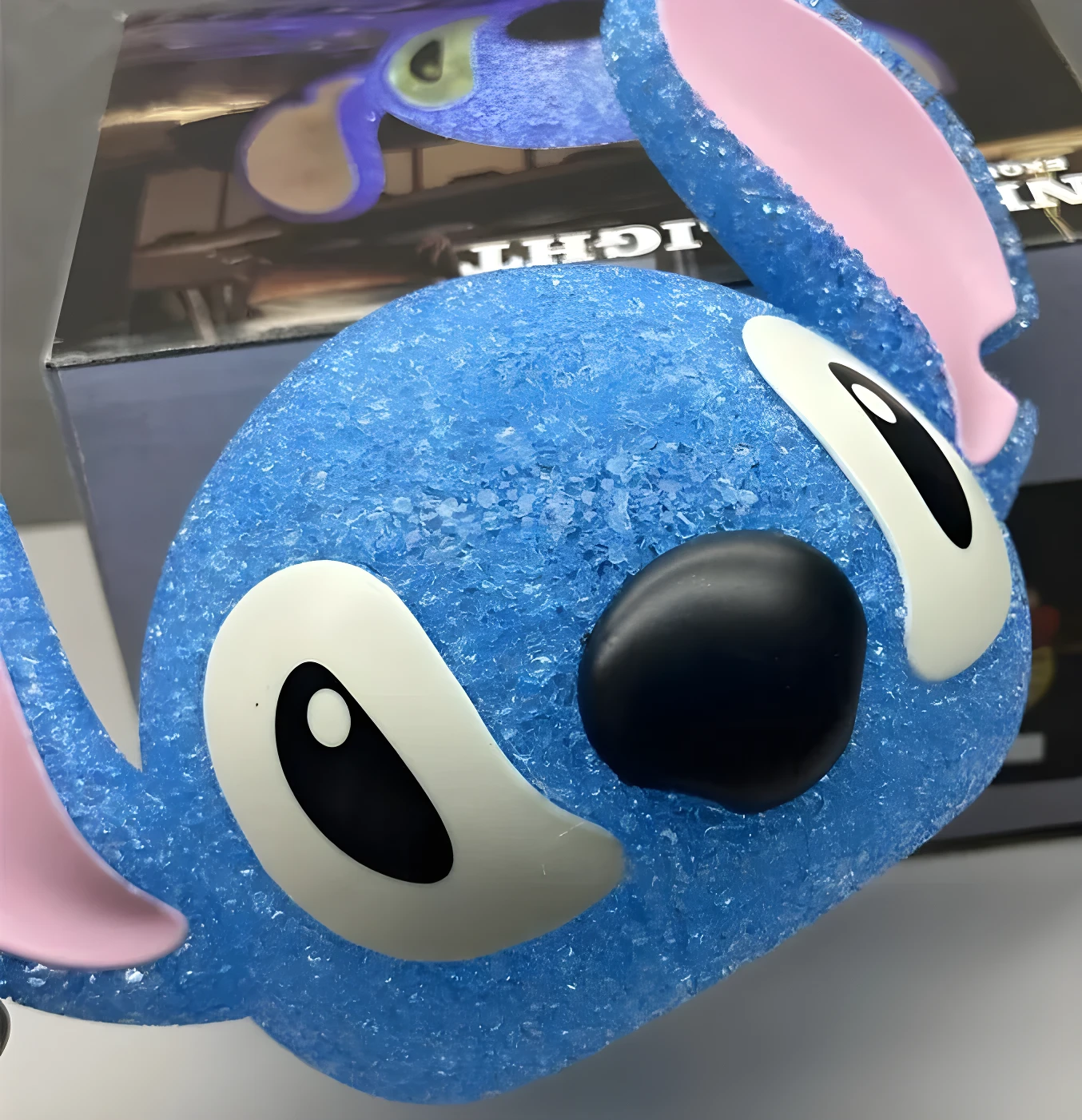 Primer plano de lámpara de noche 3D de Stitch azul textura escarchada, con ojos grandes blancos y nariz negra.