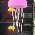 Lámpara LED Aurora de medusa rosa con tentáculos blancos, luz cálida, modo audiorítmico, en caja negra.