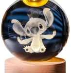 Bola cristal grabada en 3D personaje Stitch sentado, base madera clara con luz LED cálida.