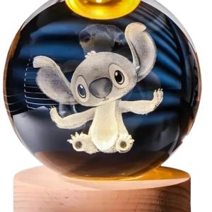 Bola cristal grabada en 3D personaje Stitch sentado, base madera clara con luz LED cálida.