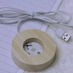 Base redonda de madera clara con LED 5050-V3 de 31mm y cable USB blanco, vista superior.
