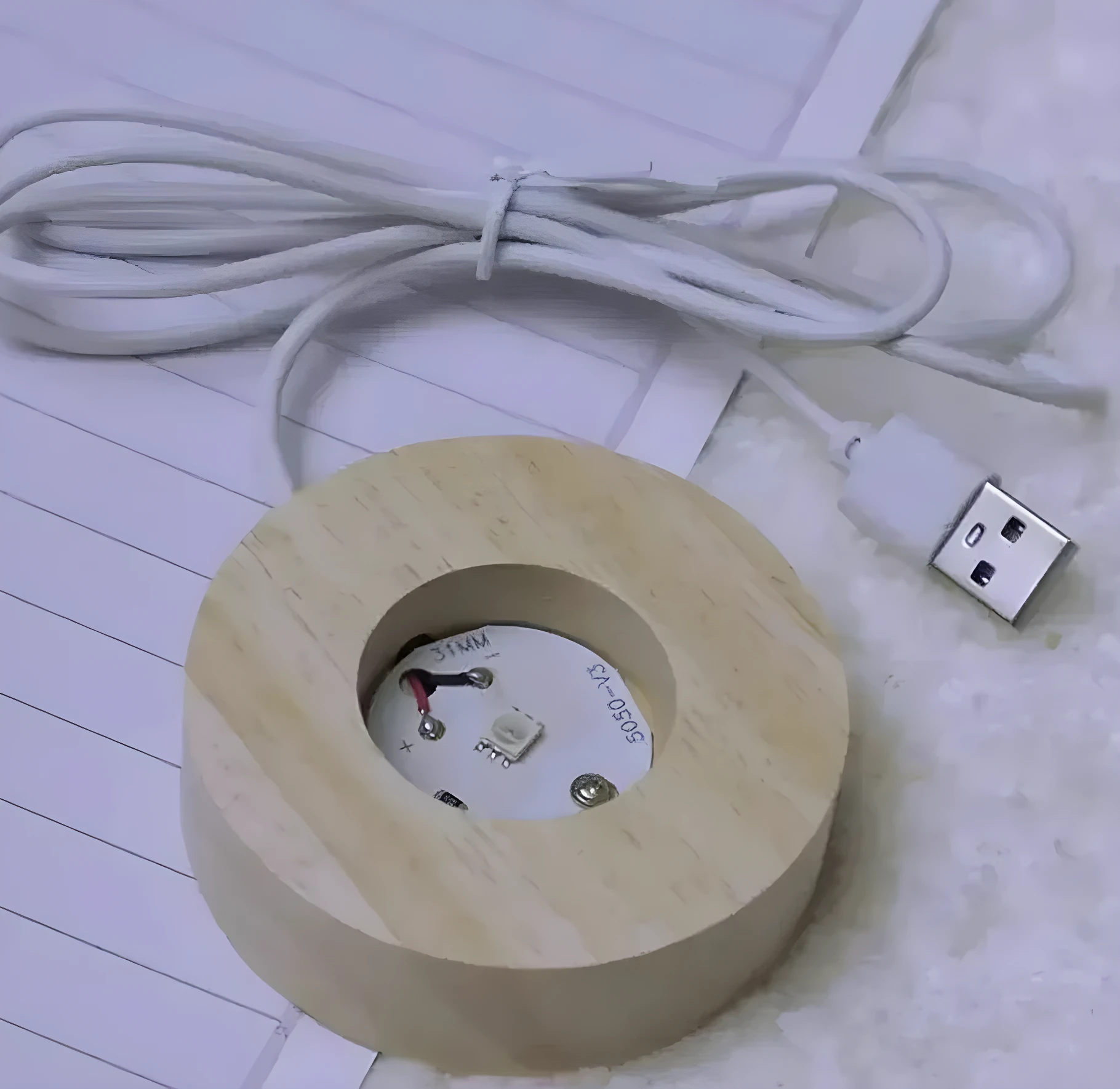 Base redonda de madera clara con LED 5050-V3 de 31mm y cable USB blanco, vista superior.