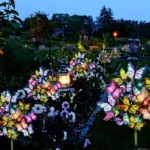 Lámparas solares de jardín con mariposas LED multicolores iluminan un sendero con linterna antigua.