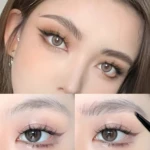 Rostro femenino con maquillaje de ojos dramático, delineado felino y cejas definidas con efecto pelo, mostrando el aplicador de micro-puntas para rellenar.