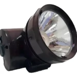 Foco frontal minero recargable, color oscuro, cabeza con reflector grande plateado inclinado hacia adelante.