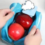 Lonchera térmica azul con dos manzanas rojas, abierta, vista desde arriba.