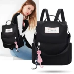 Mochila negra antirrobo para mujer, estilo casual, con llavero de gato rosa y parche blanco frontal "YIQBEI".