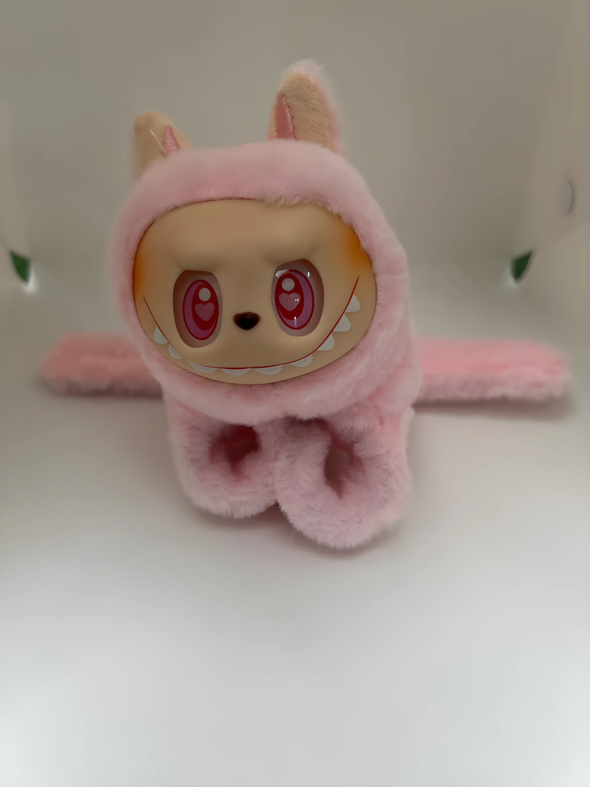 Manilla Labubu peluche rosa suave con orejas, cara de vinilo sonriente con ojos rojos de corazón, y detalle de colmillos blancos.