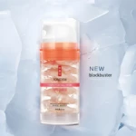 Botella de mascarilla hidratante JOMTAM en gel con pétalos rosados flotando, sobre fondo de hielo. Nuevo lanzamiento.