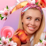 Mujer rubia sonríe, sostiene duraznos. Jarra de mascarilla labial rosa cerca. Flores de durazno.