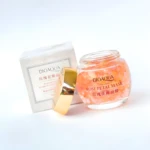 Mascarilla facial Bioaqua pétalos de rosa con tapa dorada abierta, frasco de vidrio transparente y empaque blanco al fondo.