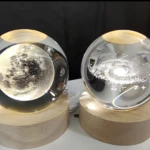 Mini lámpara de bola de cristal con diseño de galaxia y base de madera.