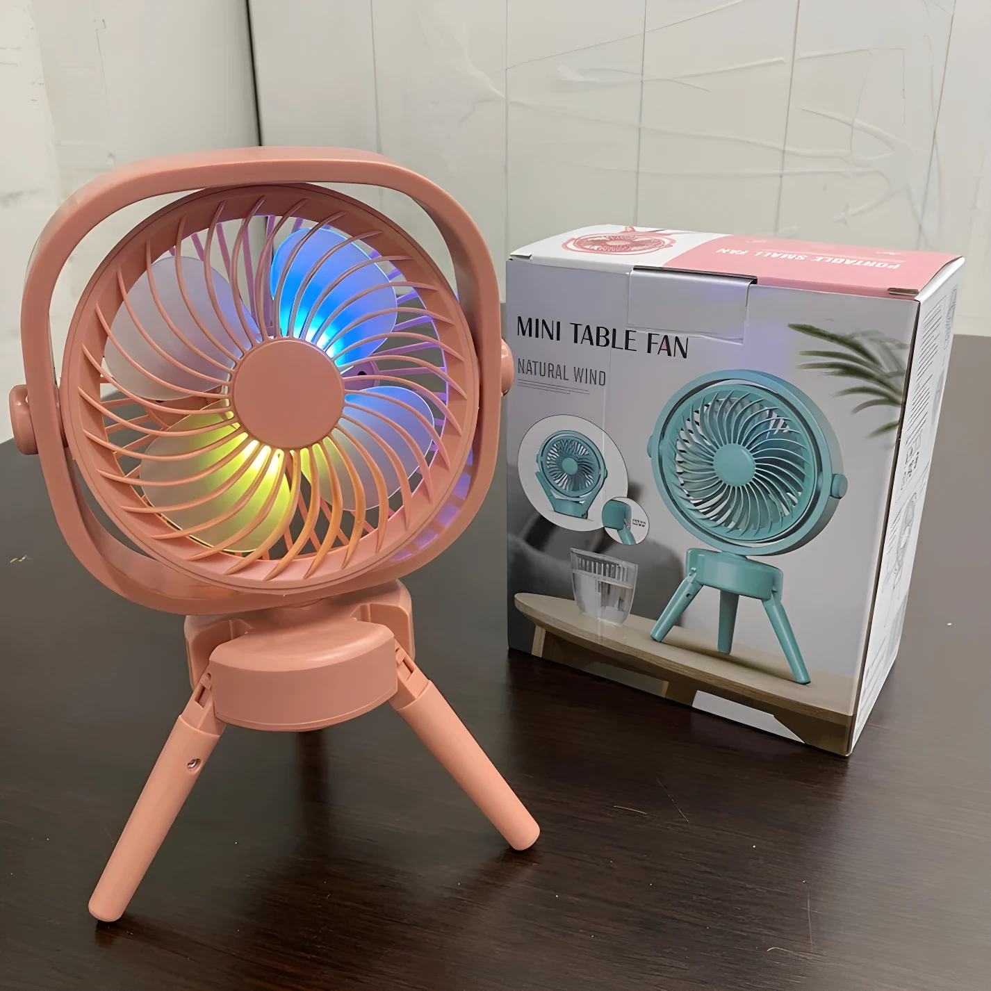 Ventilador de escritorio rosa con luz LED multicolor y base plegable.