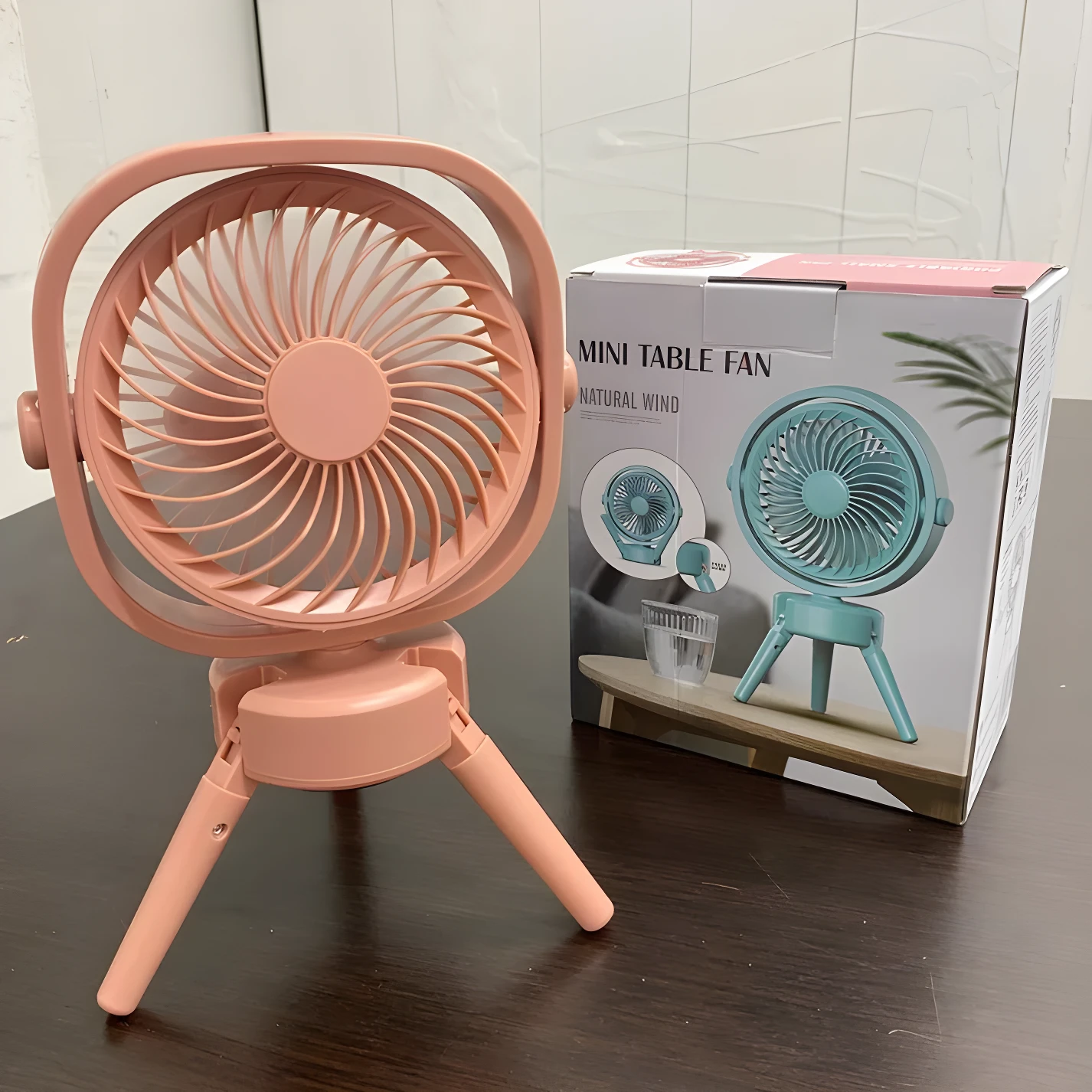 Mini ventilador rosa de escritorio plegable, diseño moderno con base tipo trípode, ideal para refrescar espacios.