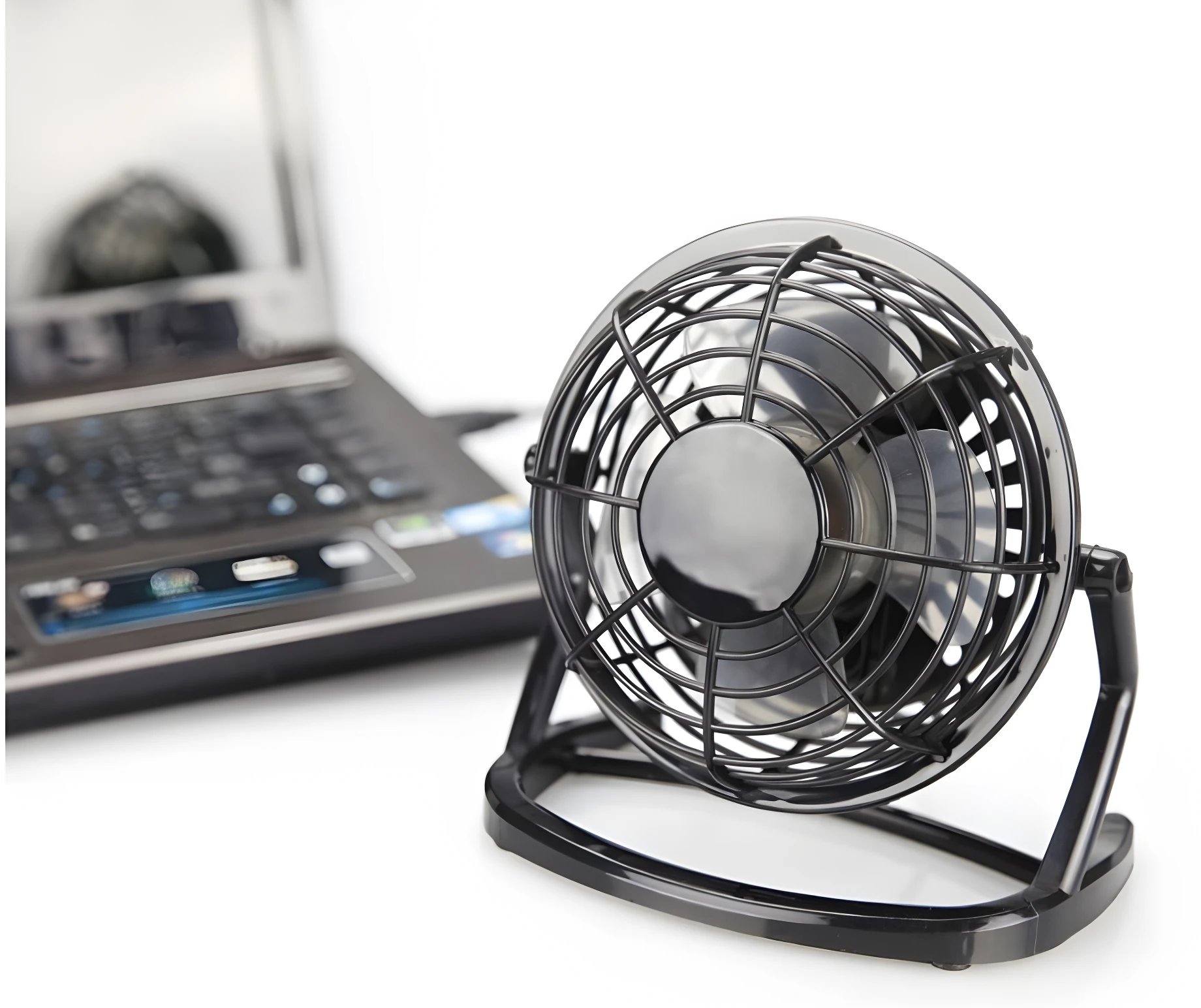 Mini ventilador USB negro con base ajustable junto a laptop.