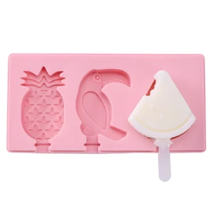 Molde rosa de silicona para helados con figuras de piña, tucán y un molde ocupado con paleta blanca de sandía mordida.
