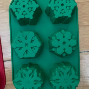Molde de silicona verde con 6 cavidades de copos de nieve para repostería navideña.