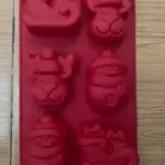 Molde de silicona rojo para repostería navideña con 6 cavidades: reno, muñeco de nieve y trineo.