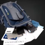 Morral de viaje azul y gris con cámara, tablet, celular y cargador portátil dentro.