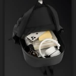 Morral negro Hh01 abierto, con celular, audífonos blancos, lentes oscuros, libros y paraguas.