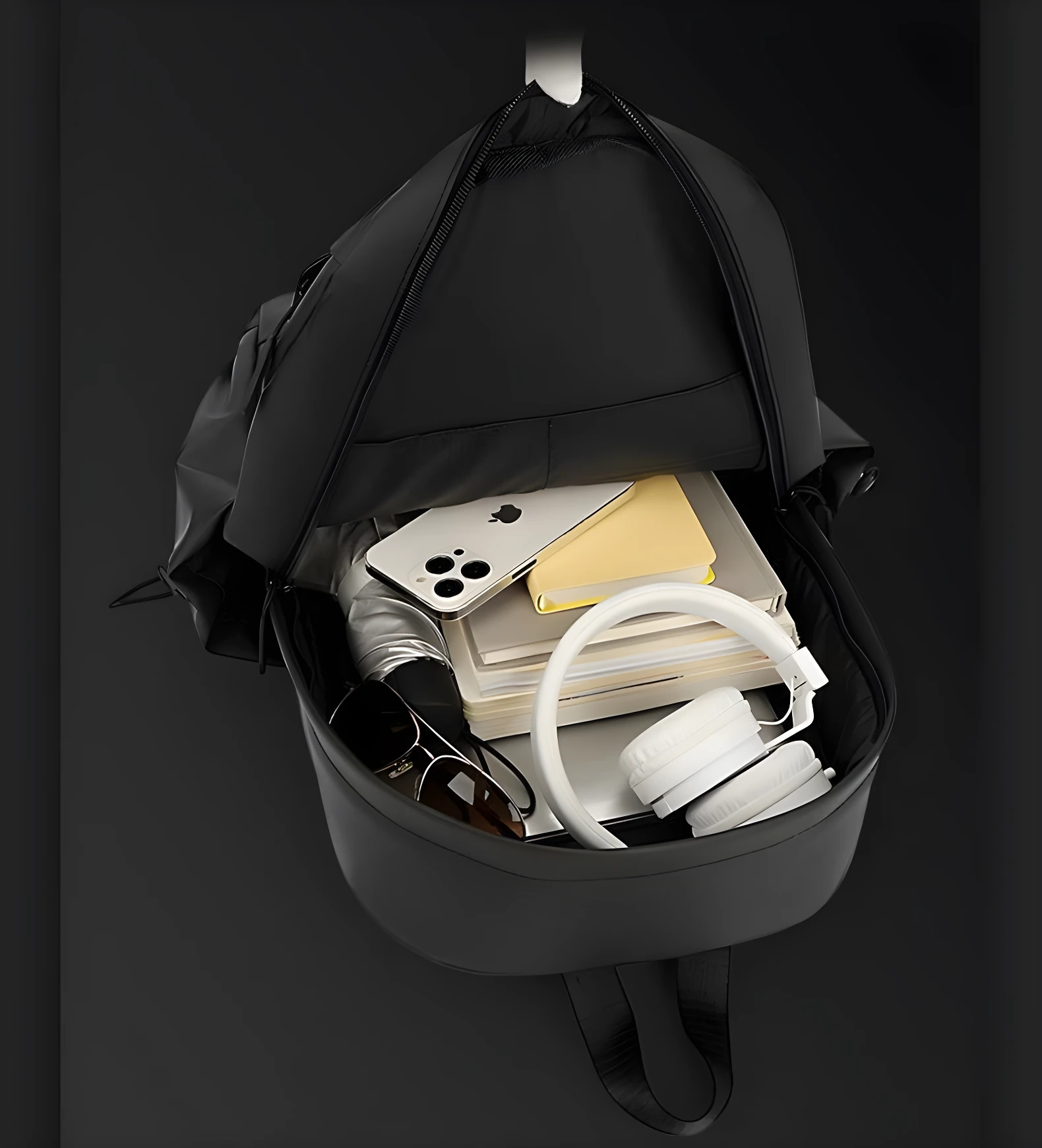 Morral negro Hh01 abierto, con celular, audífonos blancos, lentes oscuros, libros y paraguas.