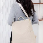 Morral beige con patrón a cuadros para dama, colgado al hombro, visto desde atrás.